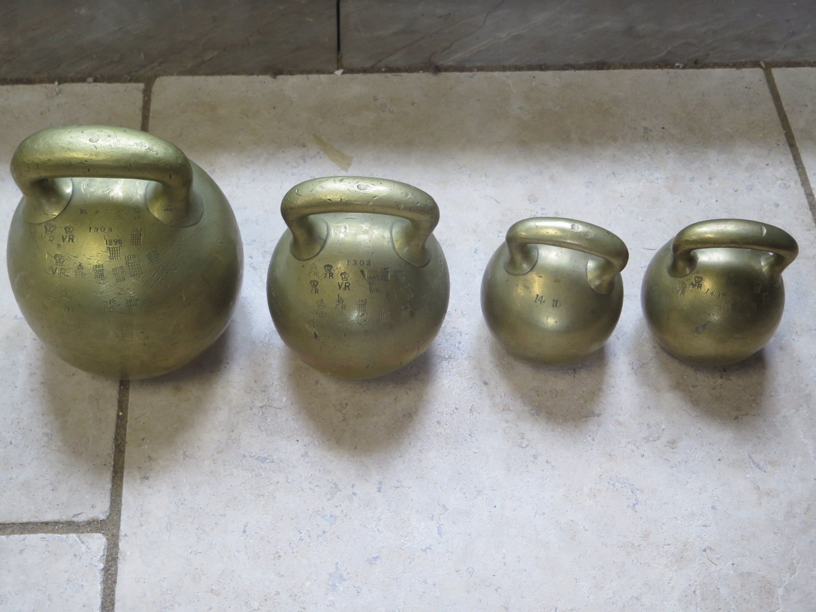 Four brass imperial ball weights, each with single loop handles, three Georgian, with 56lb , 28lb