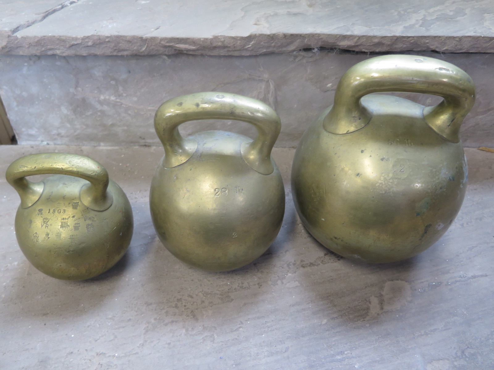 Three 19th Century brass imperial ball weights, with single loop handles, 56lb , 28 lb and 14lb