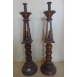A pair of Gothic type wooden candle sticks, 64cm tall