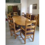 A solid oak extending two leaf table with ten ladder back chairs having brown leather seats,
