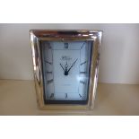 A silver framed Quartz alarm clock by R Carr 15x12cm - running, minor dents