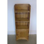 A pine bookcase with base cupboard door, 109cm tall x 38cm x 23cm