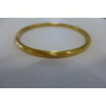 A gilt metal bangle, tests to approx 9ct, approx 11.8 grams, 8.5cm in diameter