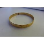 A yellow gold bangle with impressed marks, 6.5cm diameter, approx 22 grams, with scroll