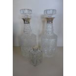 Two cut glass and engraved decanters with silver rims, 28cm tall and a scent bottle, all generally