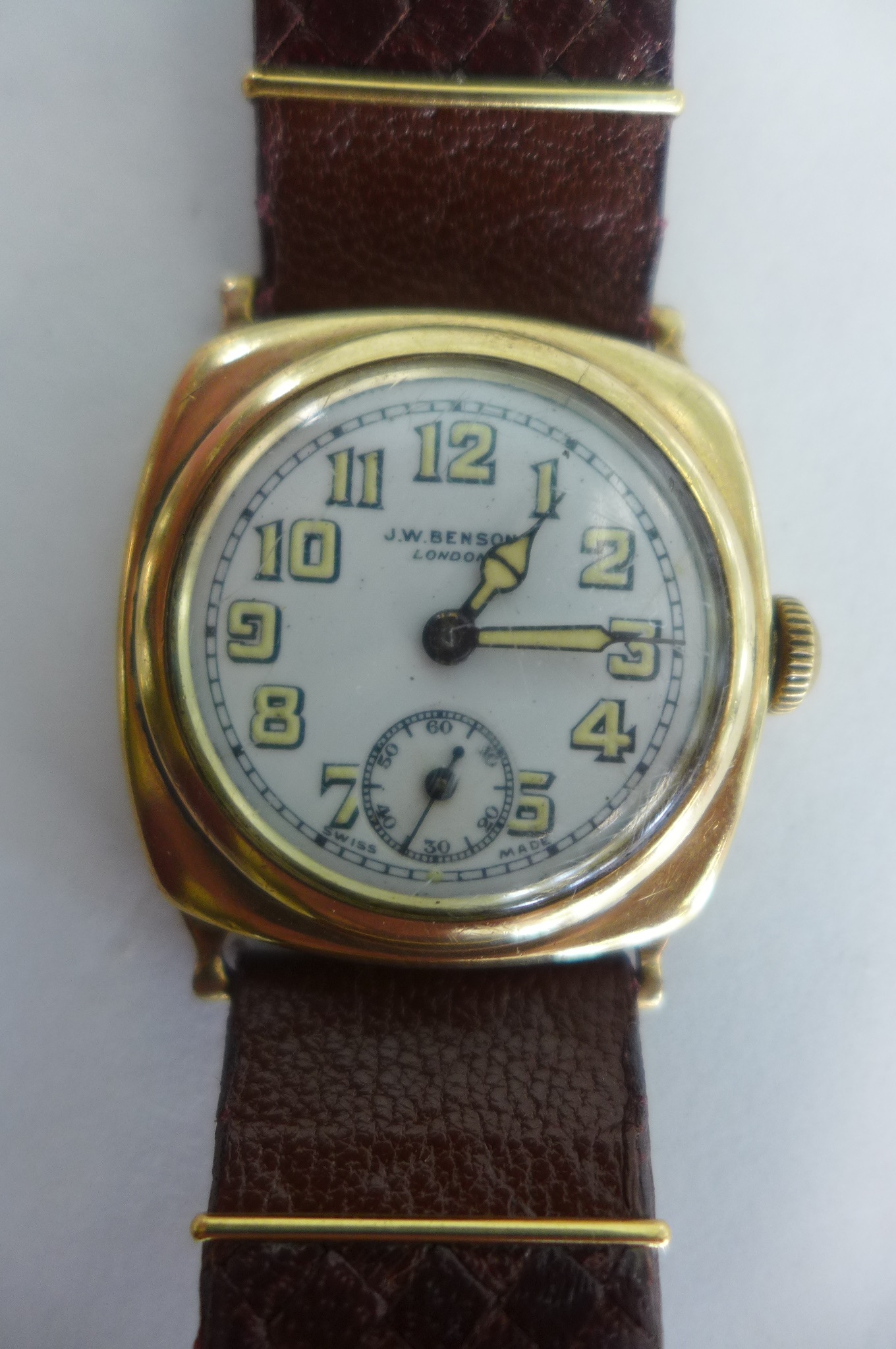 A JW Benson 9ct gold cushion cased wristwatch, white enamel face, with luninous Arabic numerals