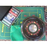 A Bakelite roulette wheel by Caro of Paris, gaming chips, dice and playing cards with baize in an