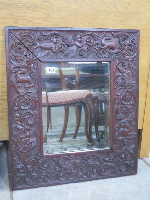 A carved hardwood mirror with a herald and animal detail, 60x52cm
