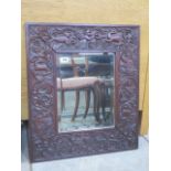 A carved hardwood mirror with a herald and animal detail, 60x52cm