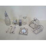 Two silver toast racks, a silver pepper, two silver napkin rings, a silver top oil jug, a silver