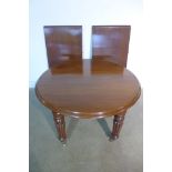 An elegant English Victorian mahogany circular extending dining table with top and two original