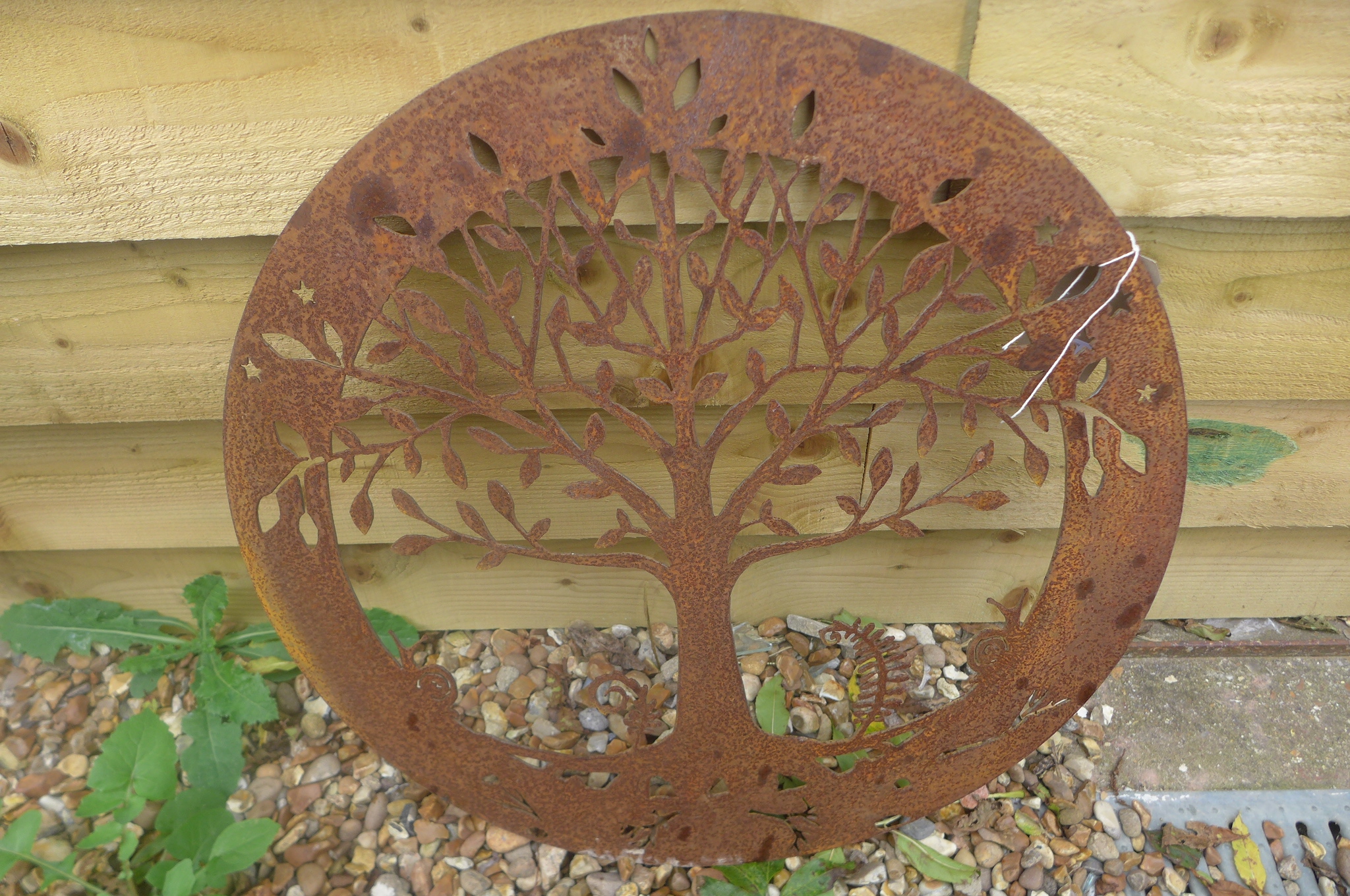 A pierced steel decorative circular wall panel depicting the Tree of Life with snails, 58.5cm