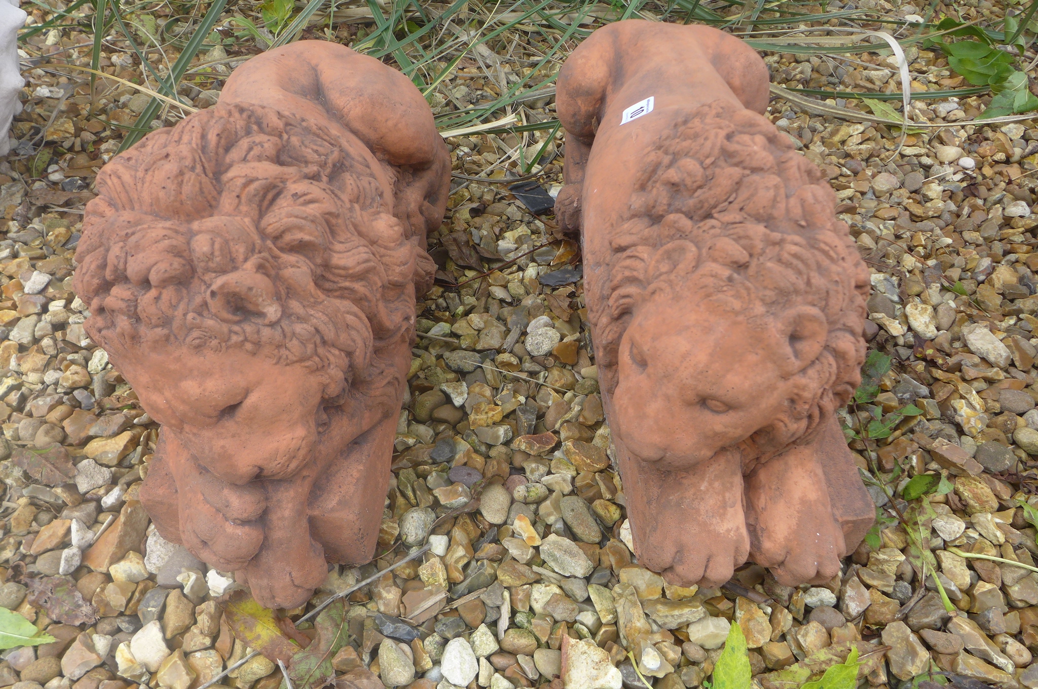 A pair of cast stone terracotta recumbent lions on rectangular bases, after canova, 45cm L x 19cm H