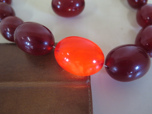 A string of cherry amber Bakelite beads, length 50cm, largest bead length 37mm, also a loose bead, - Image 2 of 5