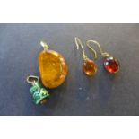 A polished amber pendant, measuring 30mm x 20mm x 9mm with yellow metal mount and pair of similar