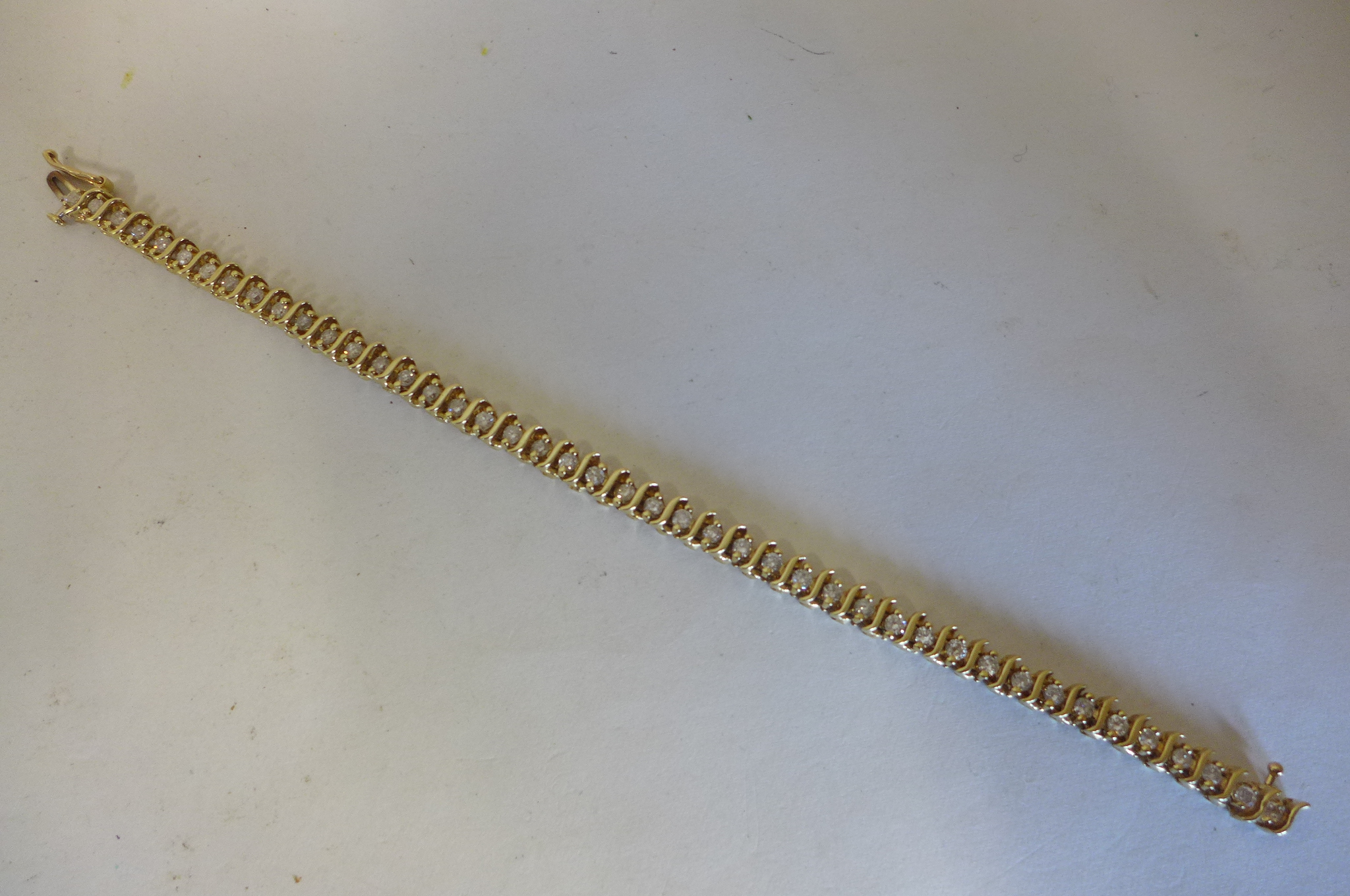 A yellow gold and diamond tennis bracelet, the gold tested to 9ct but the bracelet is not