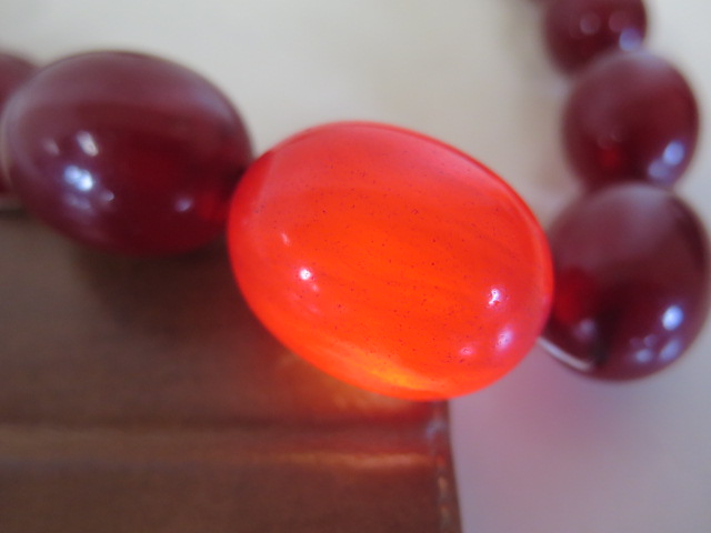 A string of cherry amber Bakelite beads, length 50cm, largest bead length 37mm, also a loose bead, - Image 3 of 5