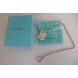 A Tiffany and Co silver dog tag on chain, with box and pouch, some minor scratches but reasonably