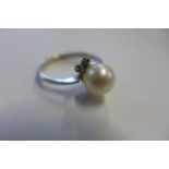 An 18ct white gold pearl and diamond ring set with a single pearl approx 8mm in diameter with four