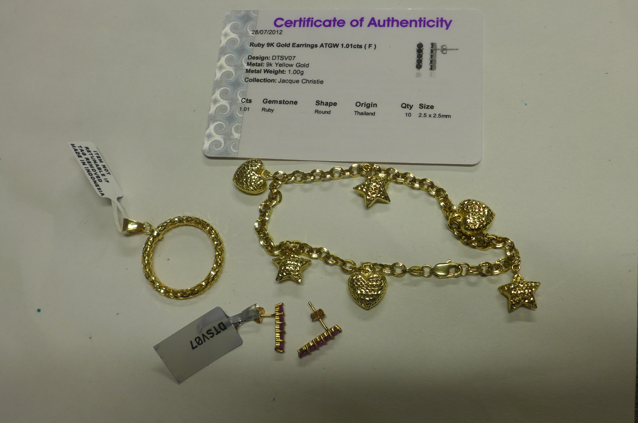 A 9ct yellow gold pendant, a pair of 9ct gold ruby earrings and a 9ct charm bracelet, total weight