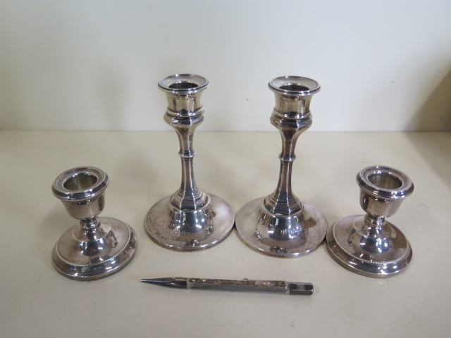 Two pairs of weighted silver candlesticks, 7cm and 13cm tall and a silver pencil