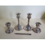 Two pairs of weighted silver candlesticks, 7cm and 13cm tall and a silver pencil