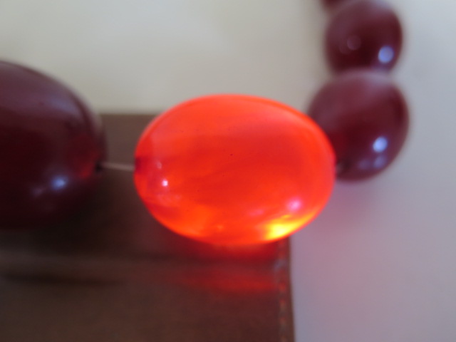 A string of cherry amber Bakelite beads, length 50cm, largest bead length 37mm, also a loose bead, - Image 4 of 5