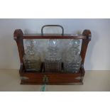 An Edwardian oak tantalus, with three odd bottles, no damage to rims but staining and fritting to