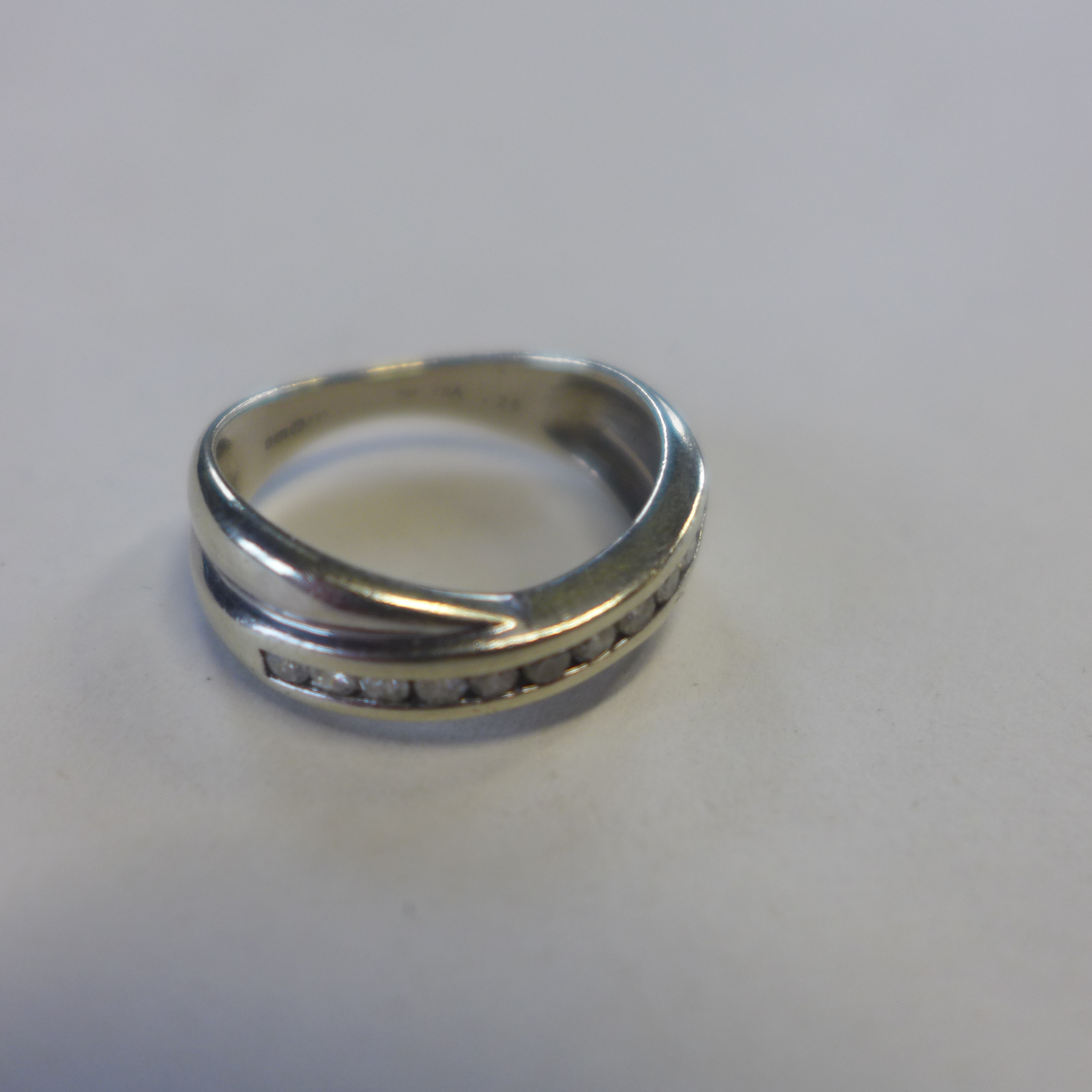 A 9ct hallmarked white gold diamond crossover band ring, 0.25ct, size L/M, approx 3.2 grams, some