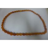 A string of Amber beads, approx 84cm long, largest bead approx 20x17mm, wear to ends of all, some