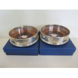 A pair of silver and turned wood wine bottle coasters, boxed - 13cm diameter, in good condition
