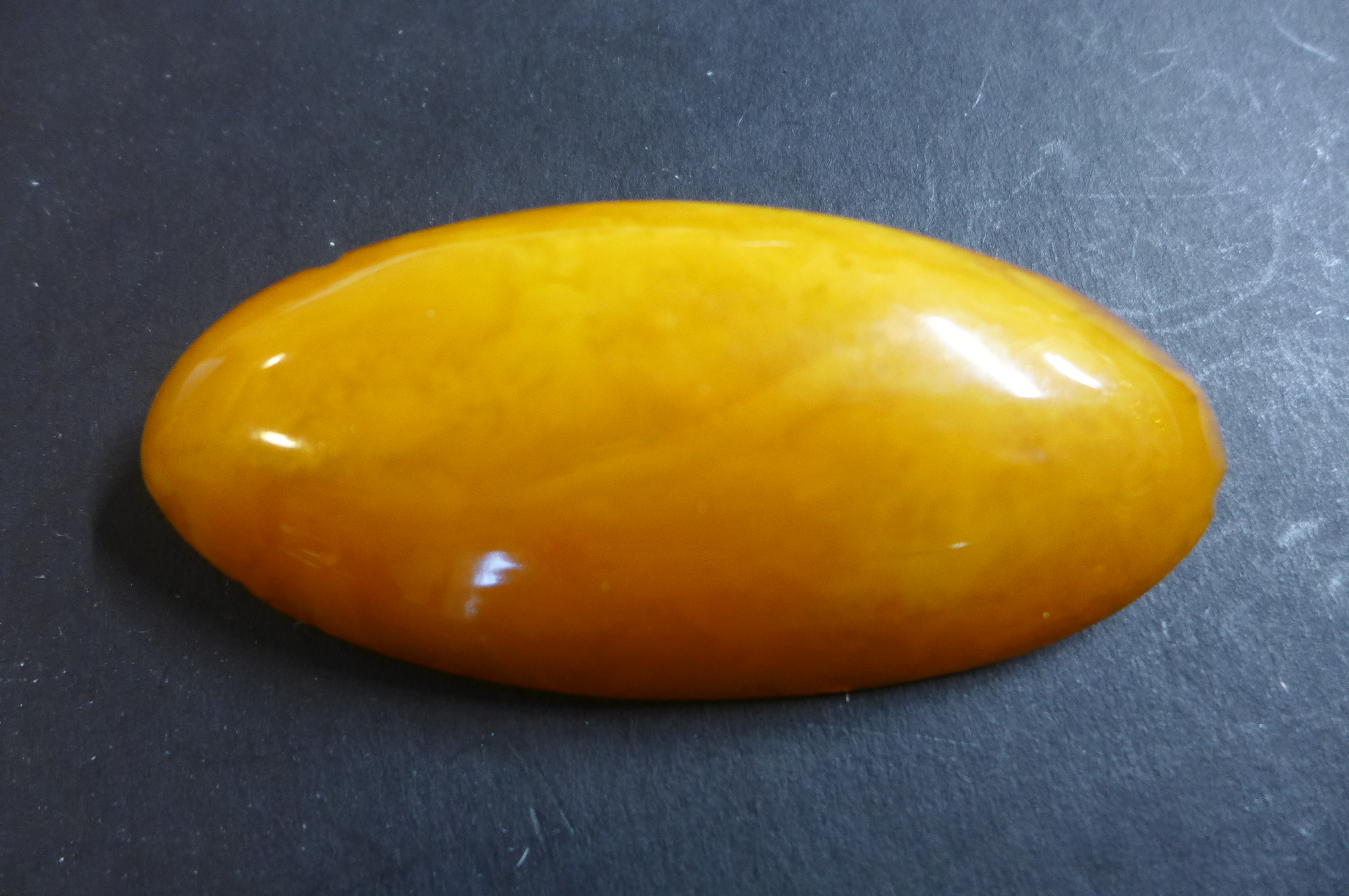 A large polished amber brooch, with 9ct fitting and steel pin, width 8cm, height 3.6cm, weight