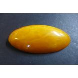 A large polished amber brooch, with 9ct fitting and steel pin, width 8cm, height 3.6cm, weight
