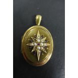 A Victorian gold mourning locket, the front set with a ruby and seed pearls in a star shape with