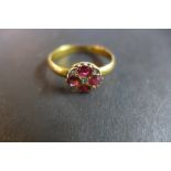 A 9ct gold ruby and diamond ring set with four rubies around a small central diamond chip and a