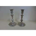 A pair of silver candlesticks with weighted bases, 19cm tall, one has a bend to base