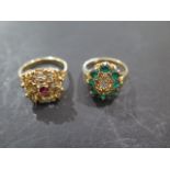 Two 18ct gold dress rings, stamped 750, one with small red stone, size M 1/2 - the second with green
