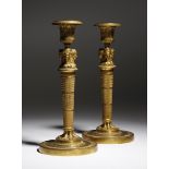 A pair of French Empire ormolu candlesticks in the manner of Jean-Demosthene Dugourc, each with a