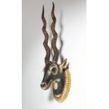 A carved and polychrome decorated wood gazelle head mount, with real horns and glass eyes, with a