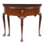 A George II mahogany demi-lune tea table, the hinged top on a single gate support, the shaped frieze