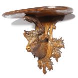 A late 19th century Black Forest carved limewood wall bracket, with a bull's head trophy mount