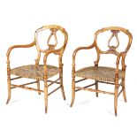 A pair of Victorian bird's eye maple open armchairs, each with a buckle back carved with leaves