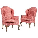 A pair of walnut wing armchairs in George II style, each with scroll arms, on shell capped