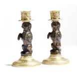 A matched pair of gilt and patinated bronze dog candlesticks, each modelled with a performing