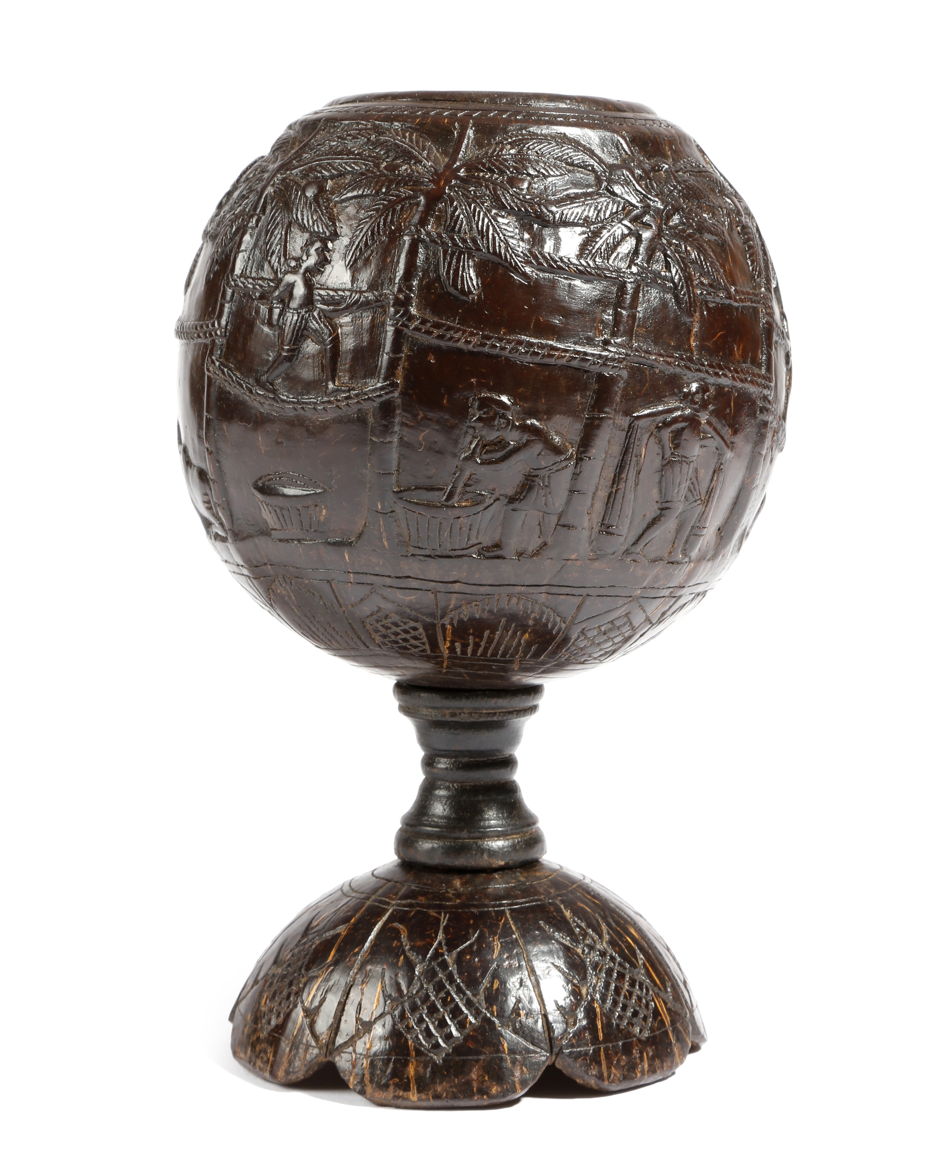 A carved coconut cup, naively carved in relief with natives in various pursuits: climbing palm