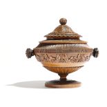 A North European treen turned and carved urn and cover, with a cone finial and leaf decoration,