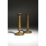 A matched pair of French Empire ormolu candlesticks, each with a detachable drip-pan, decorated with