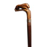 A folk art hardwood walking cane, the handle carved with a lion, with a metal ferrule, 85.4cm long.