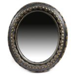 An early 18th century carved oak and ebonised oval wall mirror, with parcel gilt decoration, the