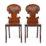 A pair of Regency mahogany hall chairs in the manner of Gillows, each with a scroll and shell carved